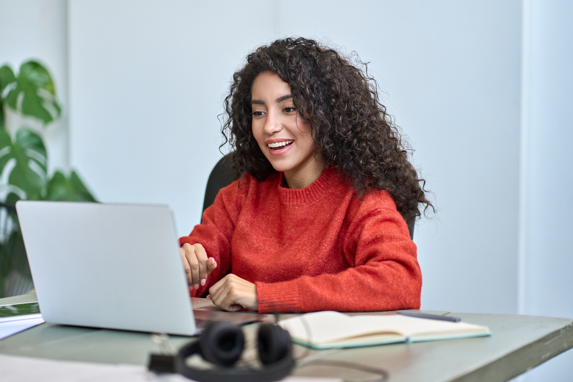 Happy surprised young latin business woman looking at laptop.